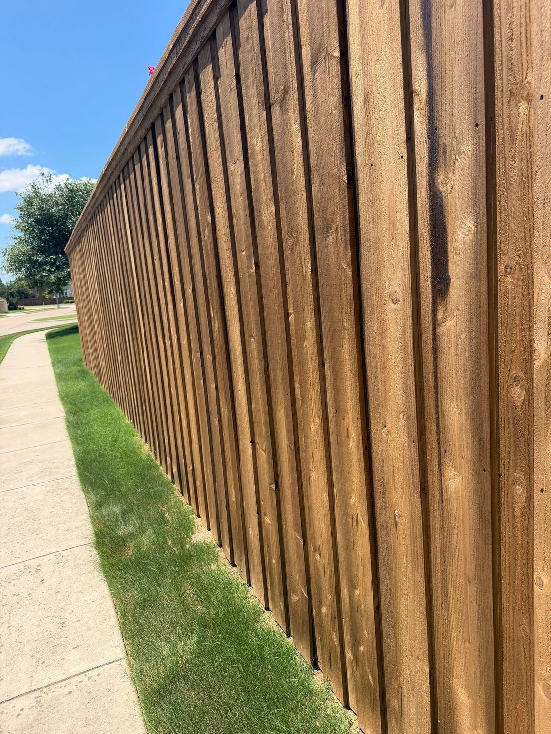 Cedar cap-rail fence running along a neighborhood sidewalk