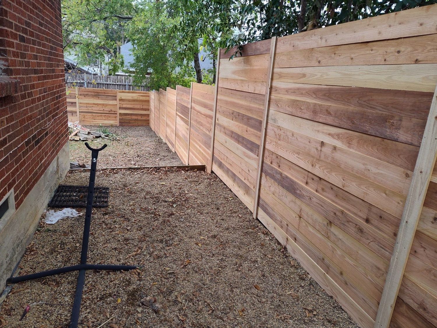 Modern horizontal cedar plank fence during installation