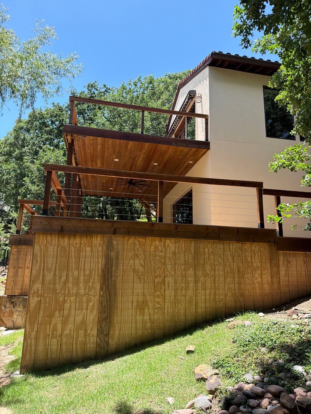 Multi-level custom wood deck with cable railing on a hillside home