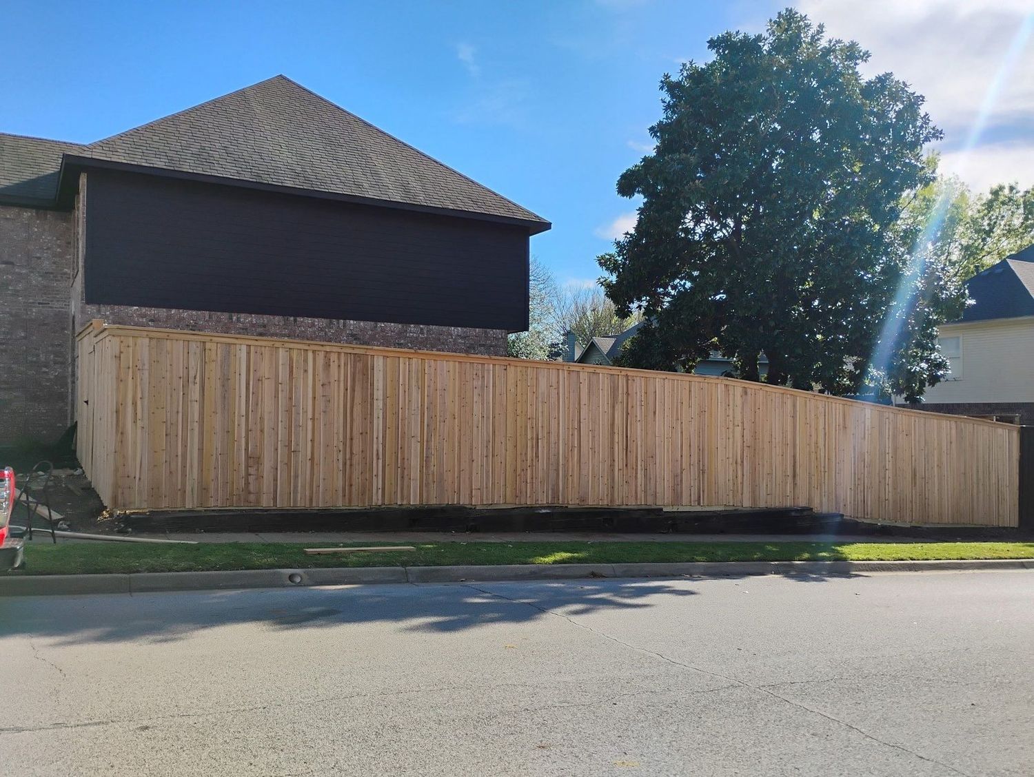 New unstained cedar privacy fence along a residential street