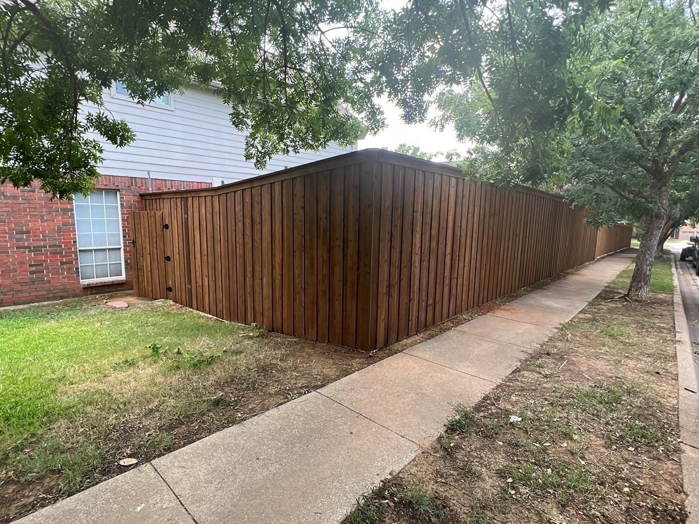 Stained cedar fence with a matching wood gate and hardware
