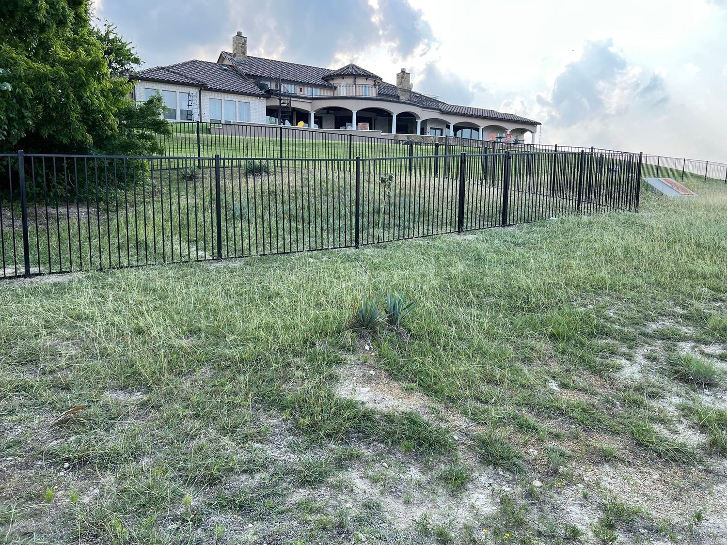 Black wrought iron fence around a hillside estate property